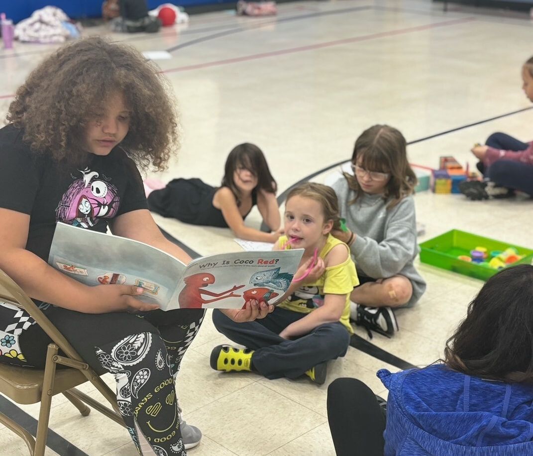 Child reads to others from the Coco the Chameleon book about air quality.