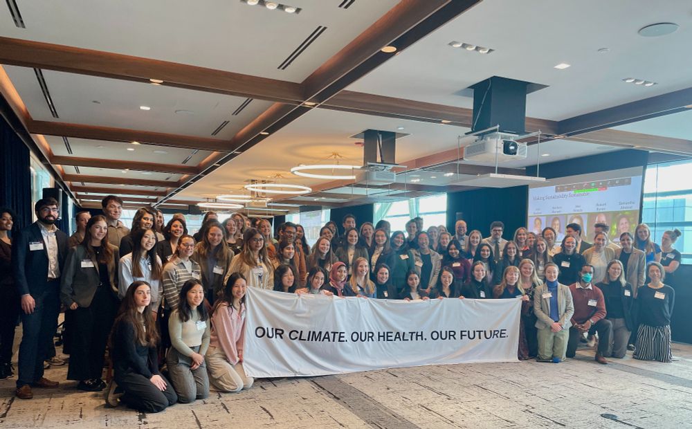 Health professionals at the 2025 Climate and Health in the 4 oh 6 conference hold a banner that says "our climate. Our health. Our future."