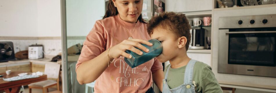Mother helping her son drink water.
