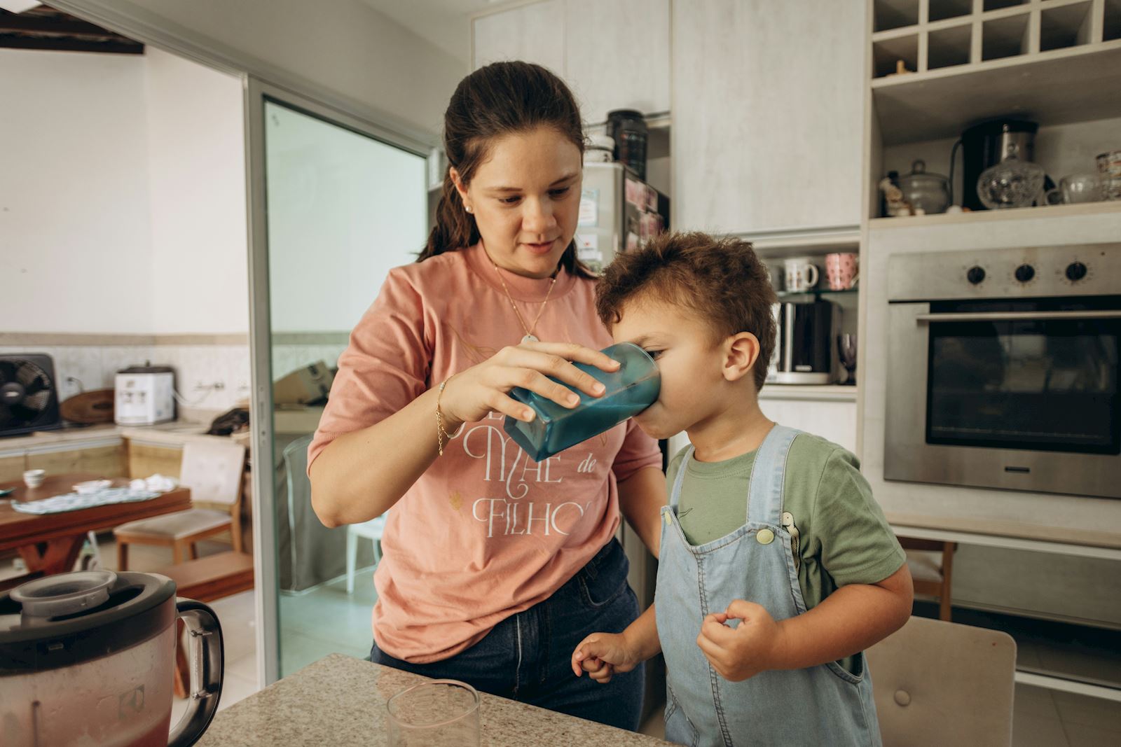 Mother helping her son drink water.